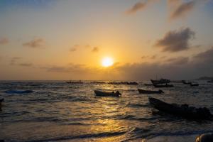 una puesta de sol en la playa con barcos en el agua en HOTEL PIEDRA VIVA en Capurganá