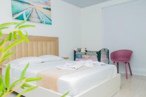 a bedroom with a white bed and a pink chair at HOTEL PIEDRA VIVA in Capurganá +4 photos