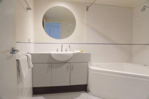 Baño blanco con lavabo, bañera y espejo en White Crystal 110, en Monte Hotham 7 fotos más