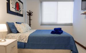 Un dormitorio con una cama azul y una ventana en Apartamento Espacioso y Acogedor - Total Rent Peru, en Lima