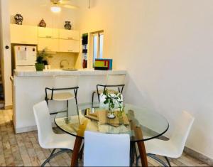 a dining room with a glass table and white chairs at Rincón Natural PA in Puerto Aventuras