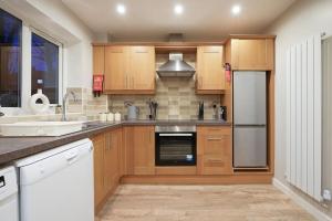 a kitchen with wooden cabinets and a sink at Stradbroke House - 5-Bed Home, Sleeps 11, Great for Group Stays & Workers, FREE Parking & Netflix in Manor