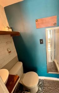 a bathroom with a toilet and a blue wall at Pop-Of-Color - Loft - Downtown Raleigh - Near NCSU in Raleigh