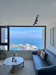 a living room with a blue couch and a large window at Departamento con Vista al mar in Viña del Mar