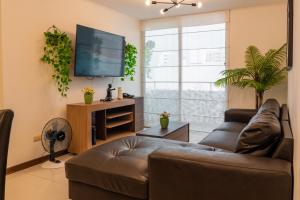 uma sala de estar com um sofá e uma televisão de ecrã plano em Apartamento Espacioso y Acogedor - Total Rent Peru em Lima