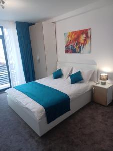 - une chambre avec un grand lit blanc et des oreillers bleus dans l'établissement ApartHotel Oltului, à Galaţi