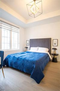 een slaapkamer met een groot bed en een blauwe deken bij Modern 4-Bed Townhome with Cinema & Roof Terrace in Oakville