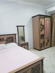 1 Schlafzimmer mit einem Bett, 2 Tischen und einem Spiegel in der Unterkunft Regnar hotel in Mansoura