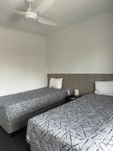 a room with two beds and a ceiling fan at Longreach Motor Inn in Longreach