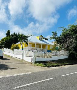 a yellow and white house with a white fence at Villa Réséda in Sainte-Anne