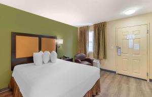 a hotel room with a large bed and a chair at Extended Stay America Suites - St Louis - Westport - East Lackland Rd in Maryland Heights
