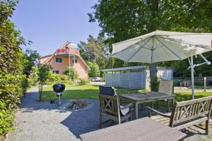 een picknicktafel met een parasol en een grill bij FeWo am Wald FeWo 03 - Balkon, Gartennutzung, Sauna in Glowe