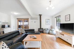 ein Wohnzimmer mit einer schwarzen Ledercouch und einem Tisch in der Unterkunft The Seascape Shack in Cowes