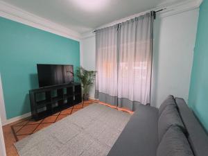 een woonkamer met een bank en een flatscreen-tv bij Charme Lisboeta in Lissabon