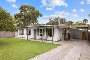 ein weißes Haus mit zwei Stühlen im Hof in der Unterkunft The Seascape Shack in Cowes