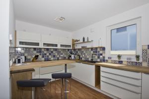 a kitchen with white cabinets and blue and white tiles at Ferienhaus Luna Haus - Terrasse, Garten, Sauna in Breege