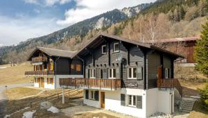 a large black and white house with a balcony at Lotus OG in Fiesch