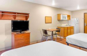 a hotel room with a bed and a television and a table at Extended Stay America Select Suites - Wilmington - West in Wilmington