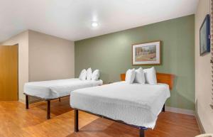 two beds in a room with green walls at Extended Stay America Select Suites - Wilmington - West in Wilmington