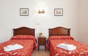 2 camas en una habitación con sábanas rojas y toallas blancas en Hostal Condestable en Madrid