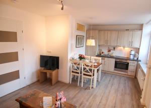 eine Küche und ein Esszimmer mit einem Tisch und einem TV in der Unterkunft Ferienwohnung Lukas Bockelmann´s Hof (ebenerdig) in Westerland
