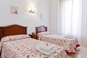 a bedroom with two beds with red and white sheets at Hostal Condestable in Madrid