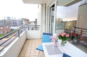 ein Balkon mit einem Tisch und einer Vase mit Blumen darauf in der Unterkunft Ferienwohnung Austernfischerin in Westerland