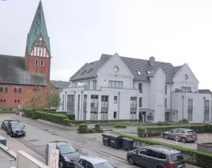 een groot wit gebouw met auto's geparkeerd op een parkeerplaats bij Ferienwohnung Neptun in Westerland