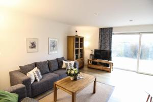 ein Wohnzimmer mit einem Sofa und einem TV in der Unterkunft Ferienwohnung Blaue Huis Erdgeschoß in Wenningstedt-Braderup