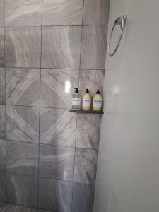 een douchecabine met drie flessen zeep op een plank bij Alem in Villa María