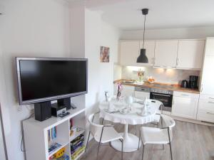 cocina con mesa con sillas y TV de pantalla plana en Ferienwohnung Jonas Bockelmann´s Hof, en Westerland