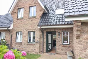 une maison en briques avec une porte et des fenêtres noires dans l'établissement Ferienhaus Ekke Nekkepenn1, à Westerland