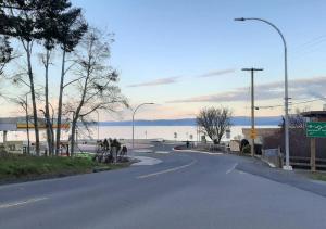 una calle vacía con el océano en el fondo en Oceanside Manor (Golf Course View), en Qualicum Beach