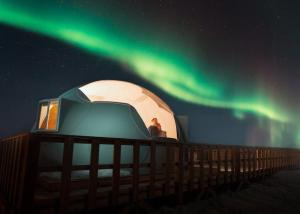 a man standing in a dome tent under the northern lights at Métis Crossing in Smoky Lake