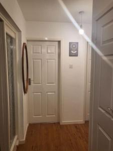 pasillo con puerta blanca y habitación con suelo de madera en Lovely apartment with free parking & Wi-Fi en Birmingham