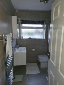 a bathroom with a sink and a toilet and a window at Lovely apartment with free parking & Wi-Fi in Birmingham
