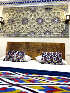 a bedroom with a bed with a patterned headboard and pillows at Bobosh Hotel in Bukhara