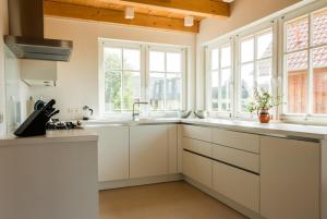 a kitchen with white cabinets and windows at Haus Wiesenweite in Born