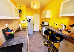una cucina con pareti gialle e sgabelli neri di Le Mans Sweet & Home a Le Mans