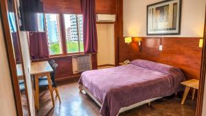 a bedroom with a purple bed and a window at Grand Hotel Rio Cuarto in Río Cuarto