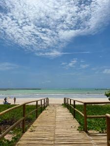 a wooden pathway leading to a beach with people on it at Naluum Milagres in Passo de Camarajibe