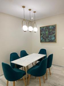 ein Esszimmer mit einem weißen Tisch und blauen Stühlen in der Unterkunft Luxueux Appart à 5 min aéroport mohamed 5 in Nouaceur