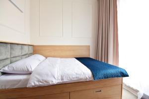 uma cama com uma cabeceira de madeira e uma janela em IVY Healthy Stay em Konstancin-Jeziorna