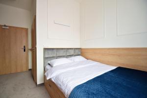 um quarto com uma cama com lençóis brancos e um cobertor azul em IVY Healthy Stay em Konstancin-Jeziorna