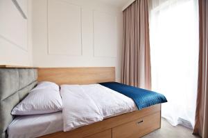 uma cama com lençóis brancos e um cobertor azul em IVY Healthy Stay em Konstancin-Jeziorna