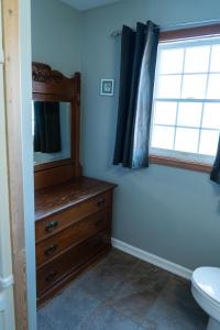 a bathroom with a dresser and a toilet and a window at Albert's in Shelburne