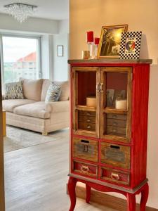 a red cabinet with a mirror in a living room at Departamento Elegante en Torre Leloir in Villa Marini