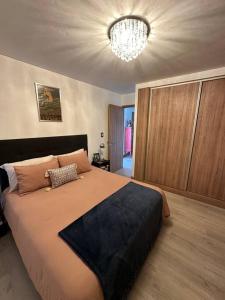 a bedroom with a large bed and a chandelier at Departamento Elegante en Torre Leloir in Villa Marini