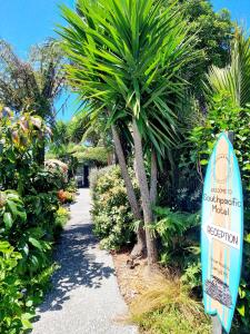 a surfboard in a garden next to a palm tree at Southpacific Motel in Whangamata