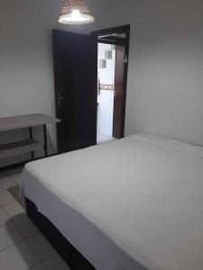 ein Schlafzimmer mit einem weißen Bett und einem Tisch in der Unterkunft Apartamento pé na areia 5 pessoas (Beto Carrero). in Penha